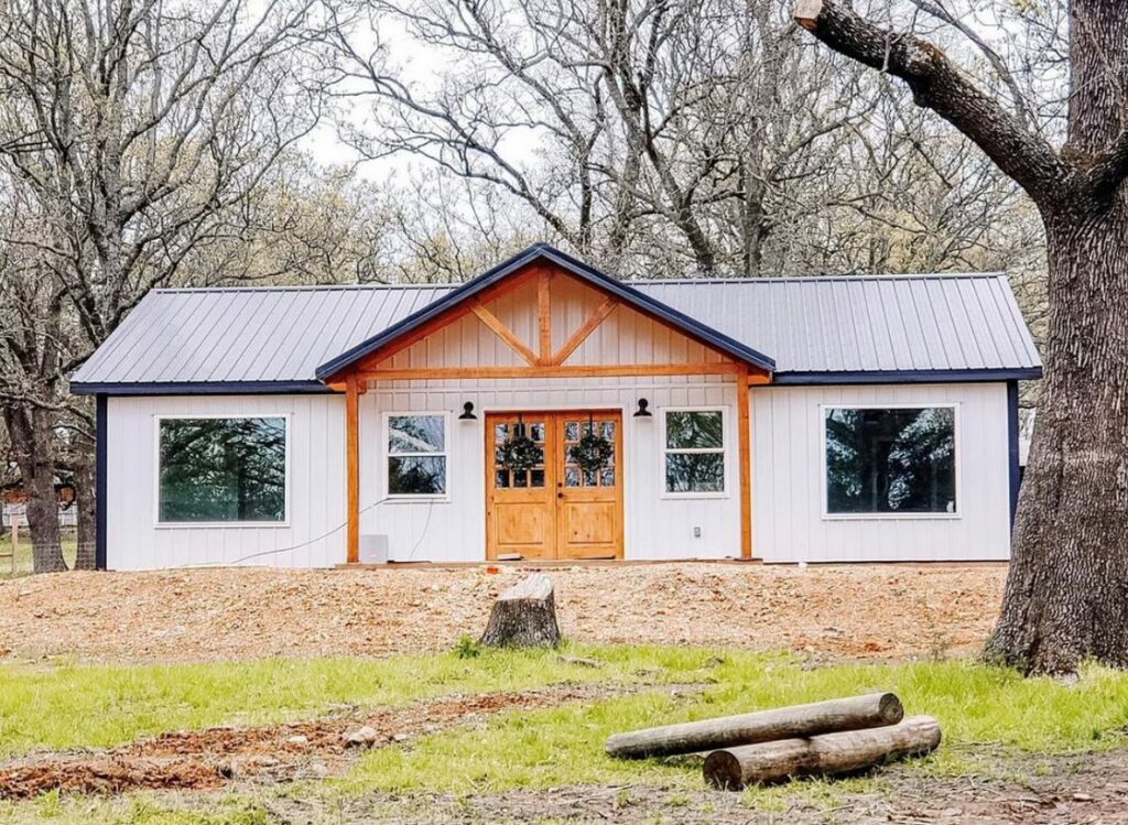 Front image of the exterior featuring black roof and white metal siding. 