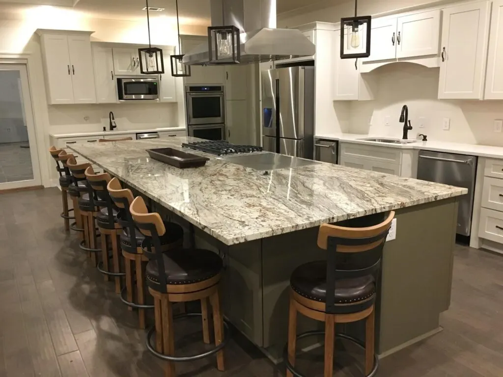 View of kitchen granite counter-top with seating, white cabinets, and stainless steel appliances