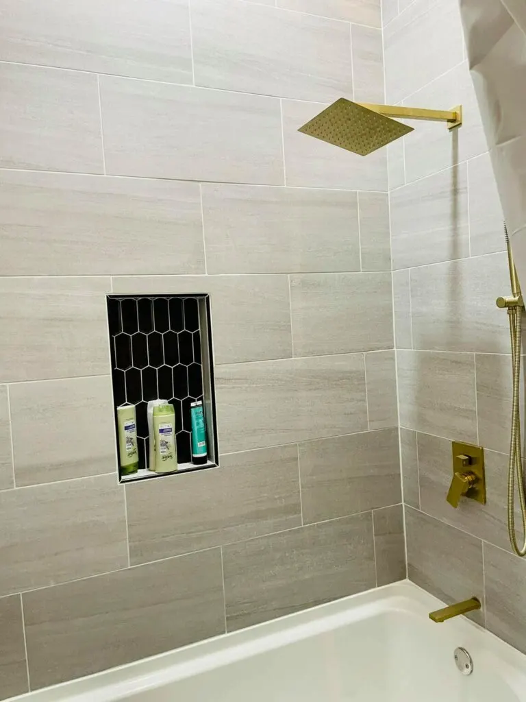 Sandy colored tile shower with gold fixtures.