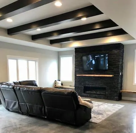 Living room shot with wood beams and black fireplace with mantel