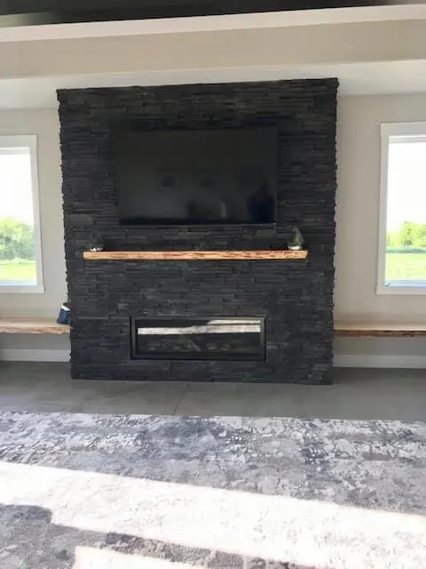 Black stone fireplace with cedar mantel and accent benches