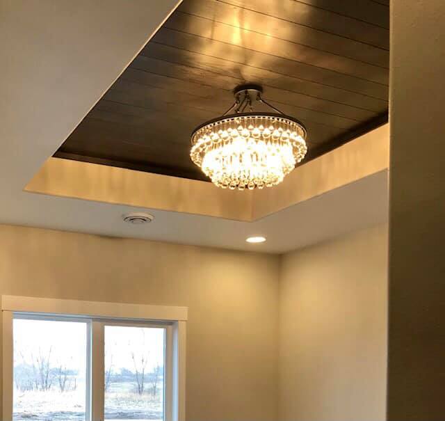 Chandelier in the entryway with wood-planked ceiling