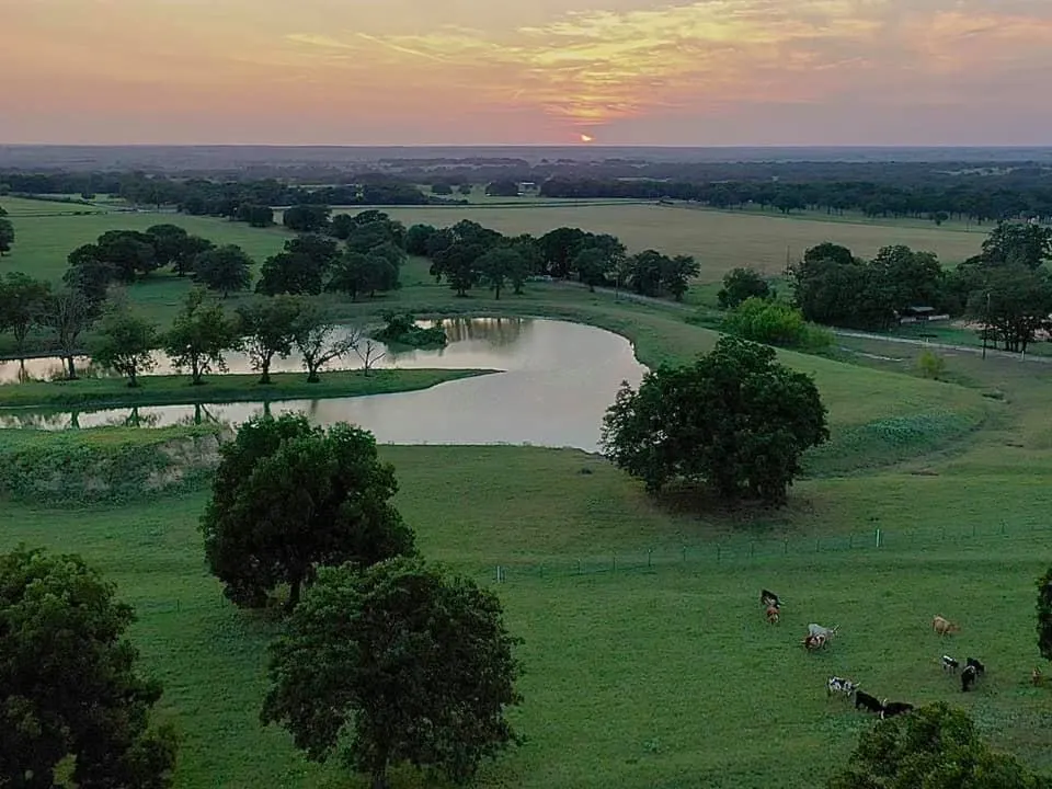 Unique Texas Hillside Barndominium with a Gorgeous View of this pond that reflects the sunset
