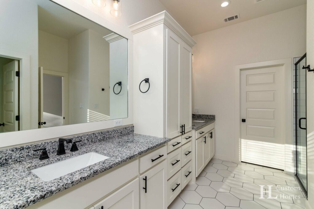 Master bathroom with granite countertops and all-white walls, cabinets, and floor tiles 